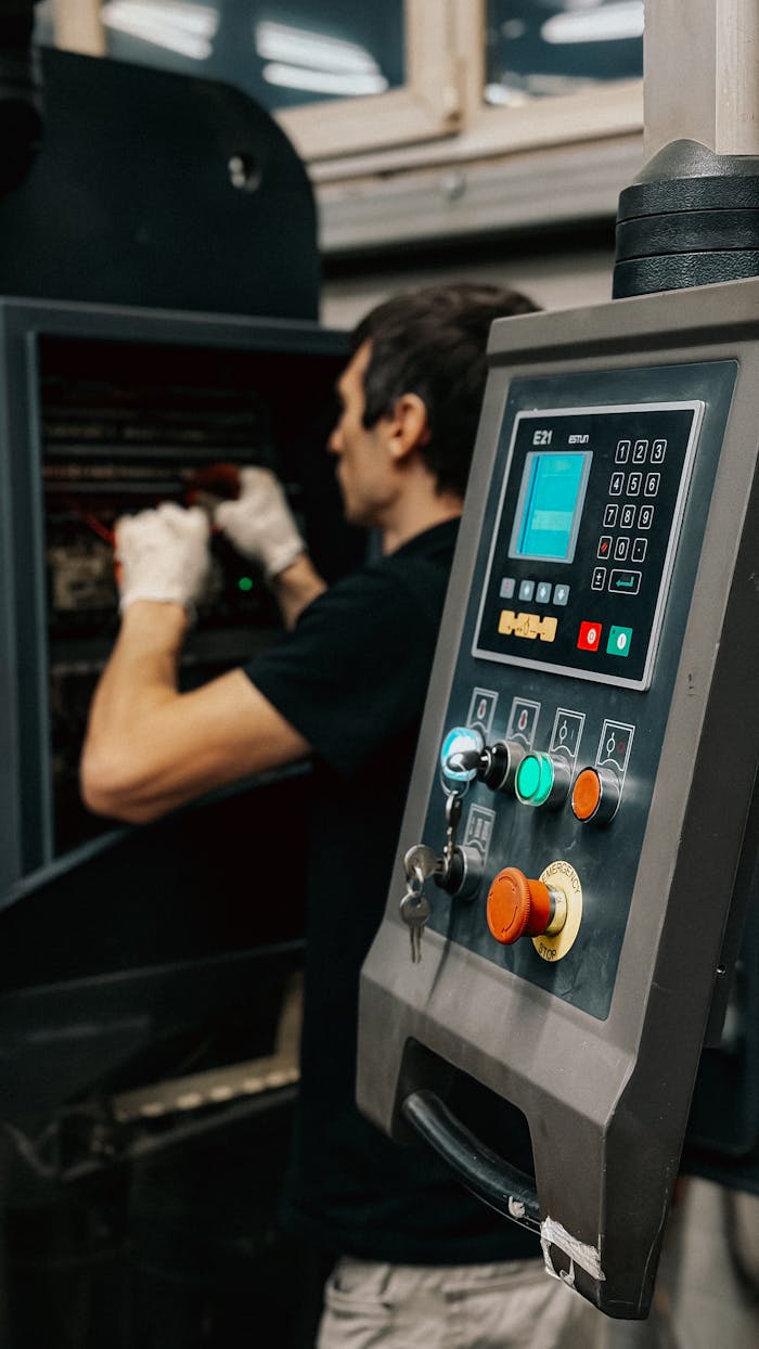 services-05 Technician using a control panel to manage machinery operations in a factory.